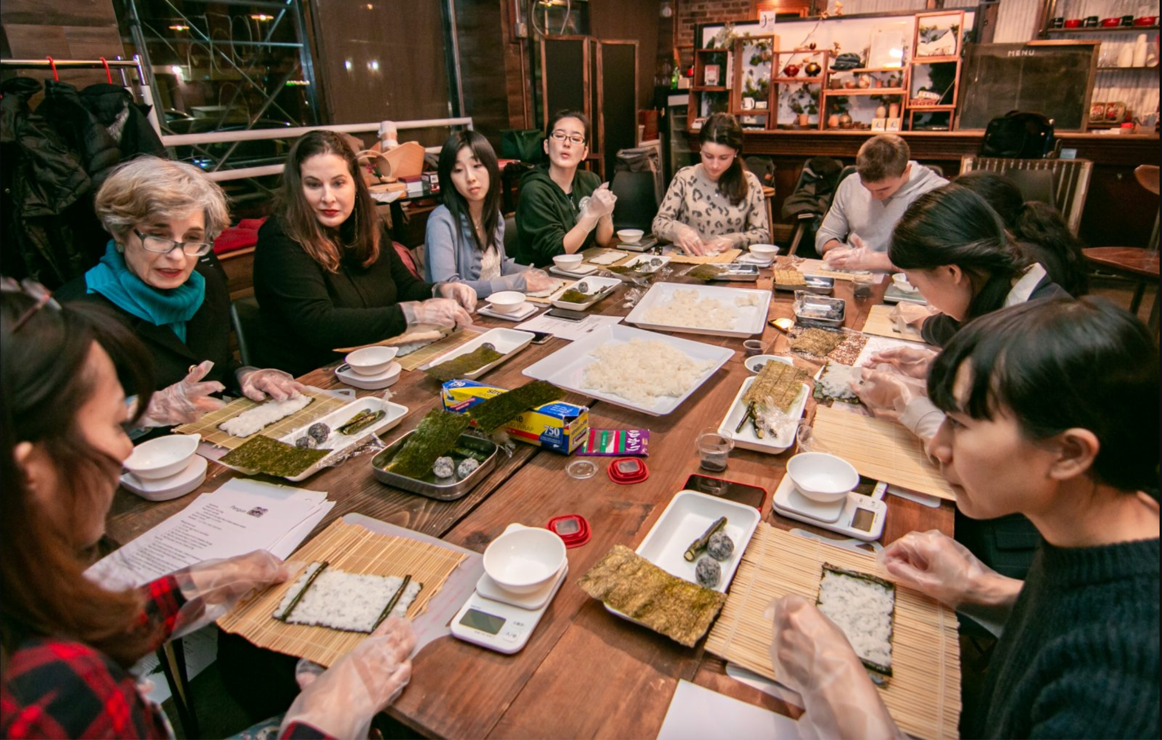 A lively culinary team-building event with a diverse group of participants engaged in a sushi-making workshop.