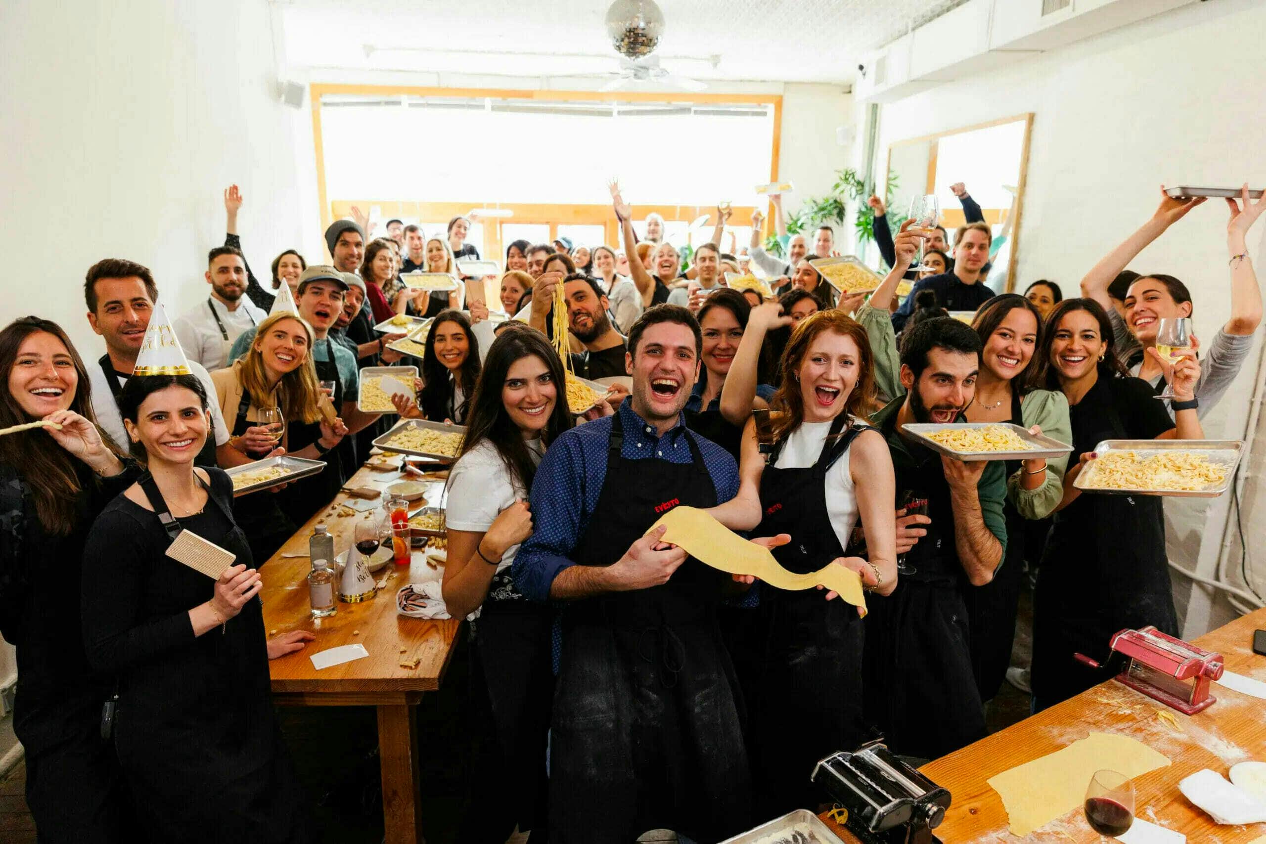 a large group of people showing the pizza they made together