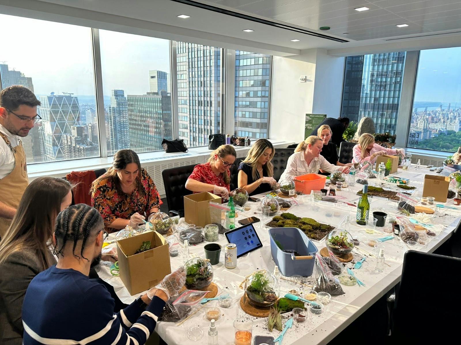 Group of people engaged in a terrarium-making workshop in a brightly lit office space