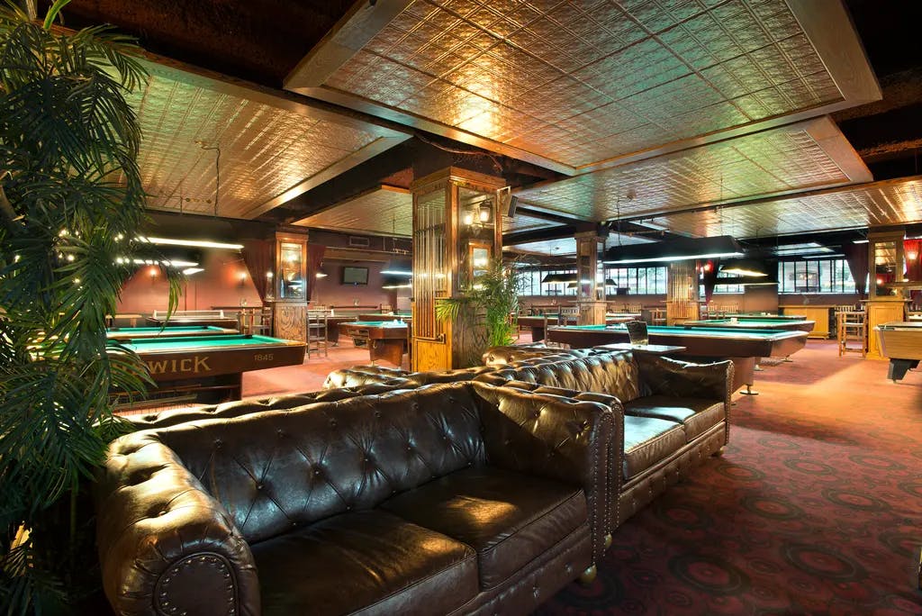 a pool hall with large leather coaches and pool tables in the background