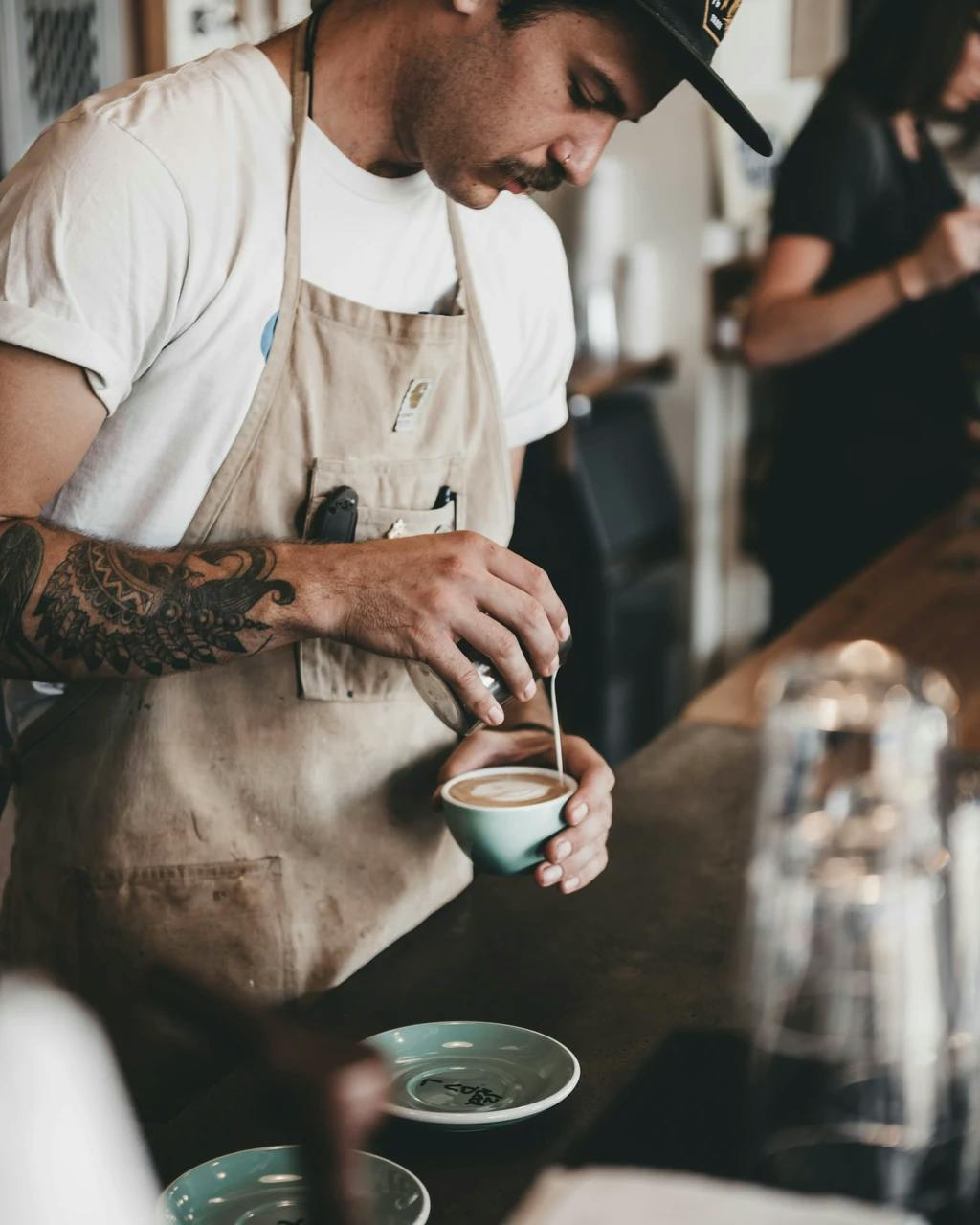 a barista pouring milk into a coffee cup