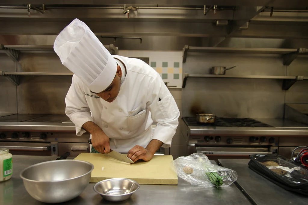 a chef cutting something on a tray in the kitchen