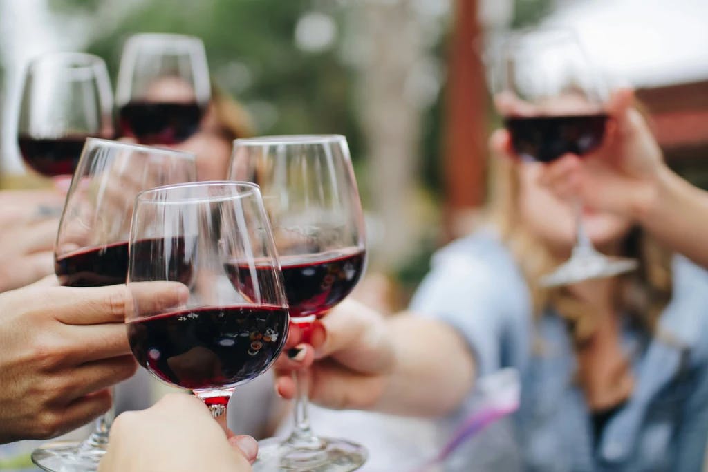 a close up of people cheersing glasses of wine