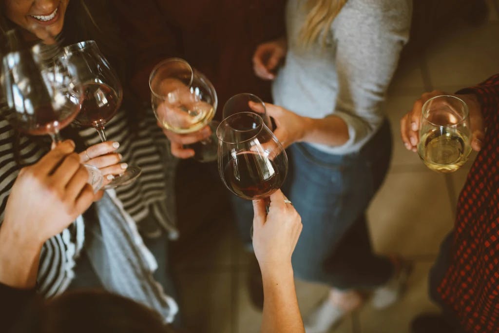people in a circle, cheersing glasses of wine