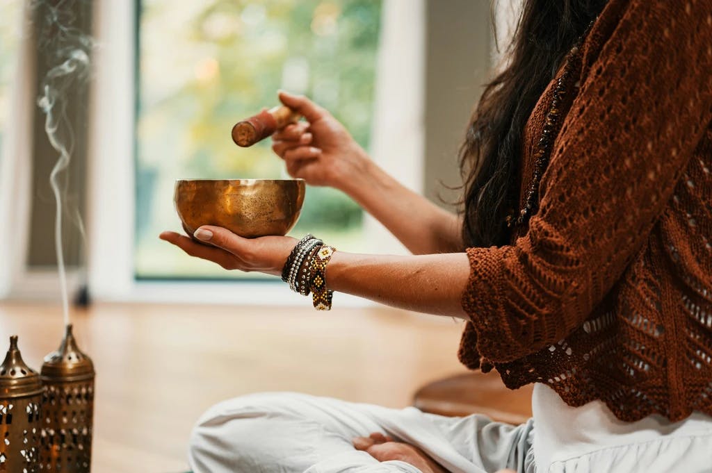 a person holding a sound bowl and burning incense while meditating