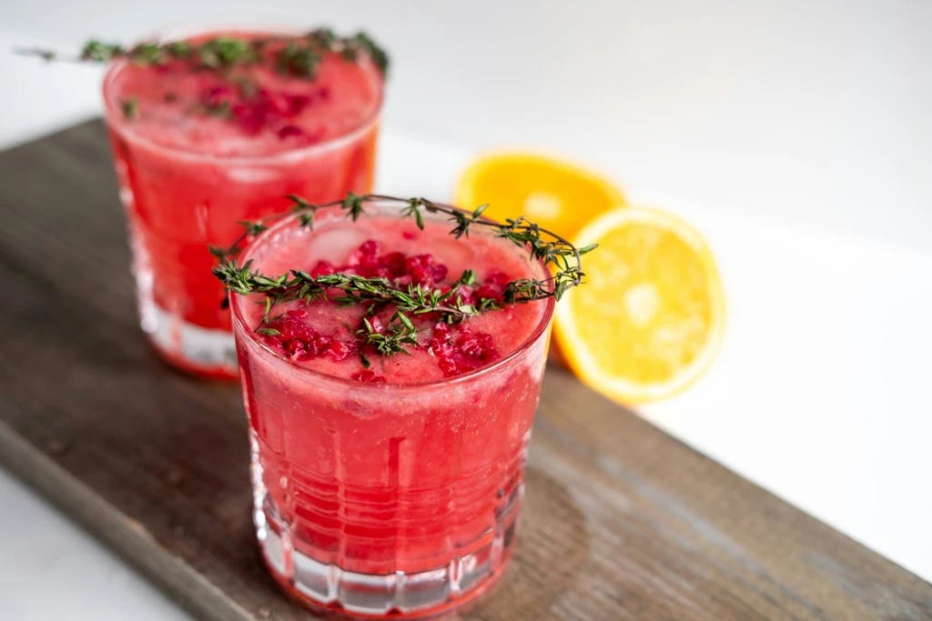 a red drink with a seasoning garnish