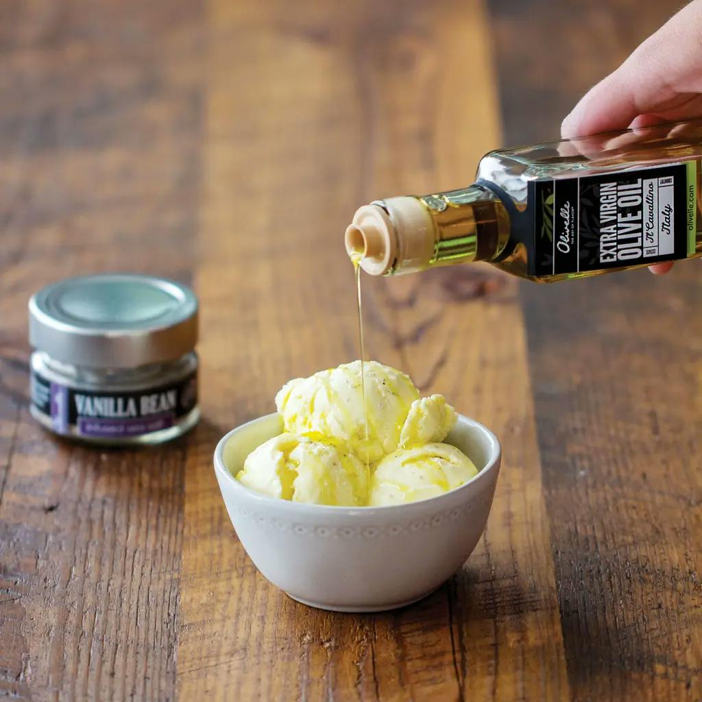 someone pouring olive oil on a bowl of ice cream