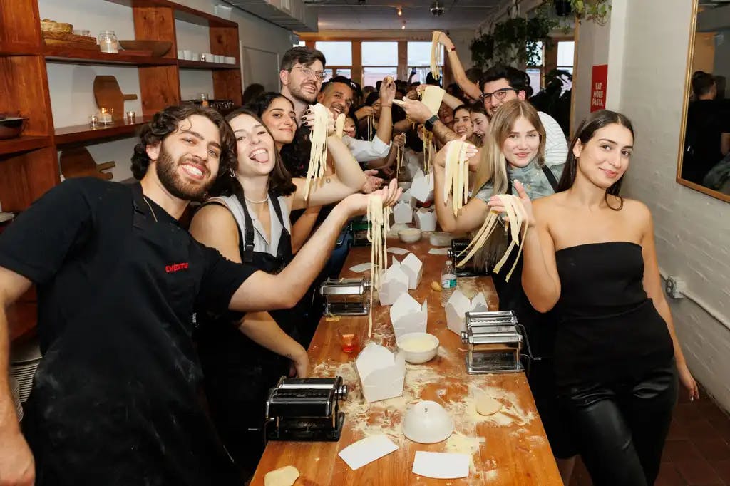 a group of people showing the camera the pasta they made