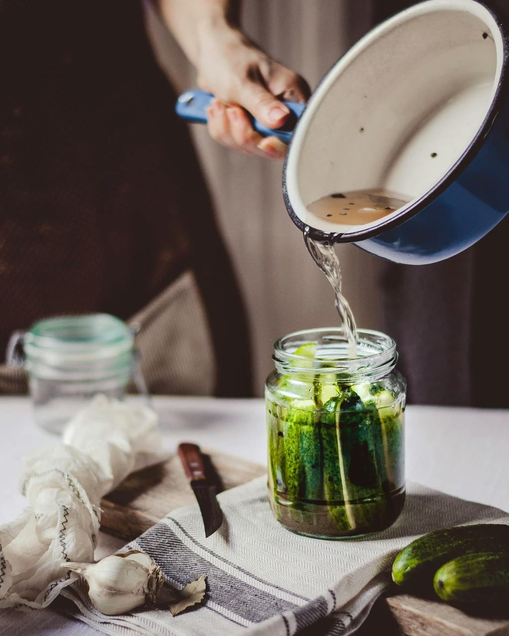 somone pouring prine into a pickle jar for homemade pickles