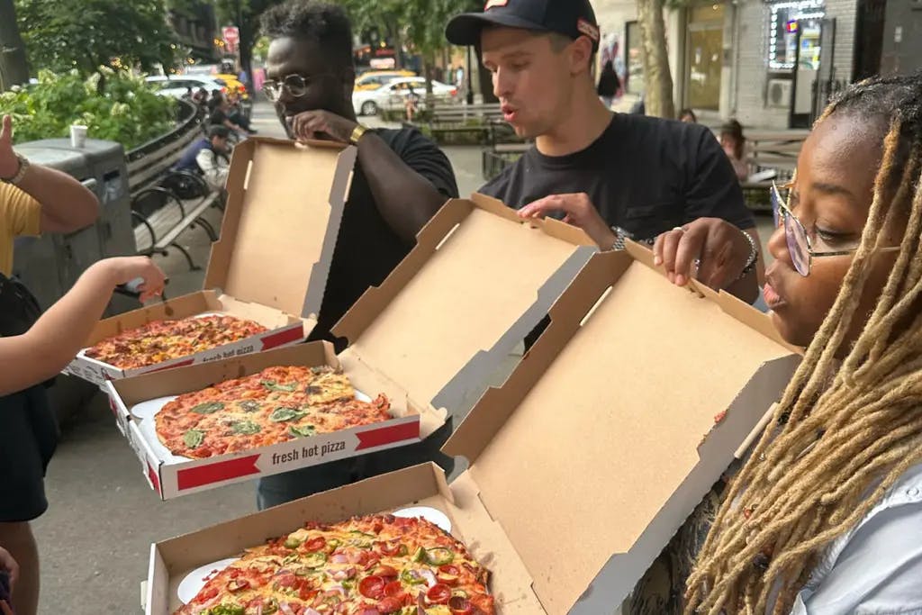 three people holding open different boxes of pizza