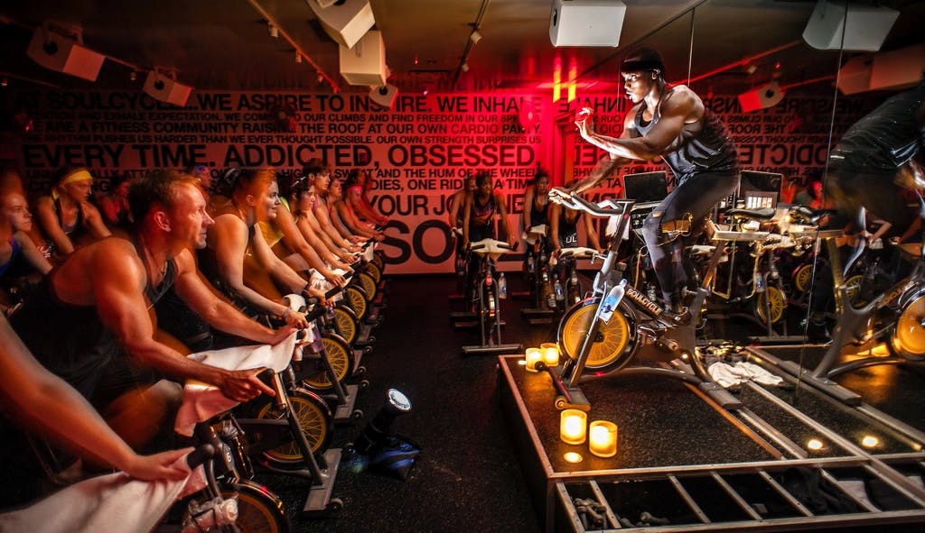 An instructor on a bike leading a class full of people