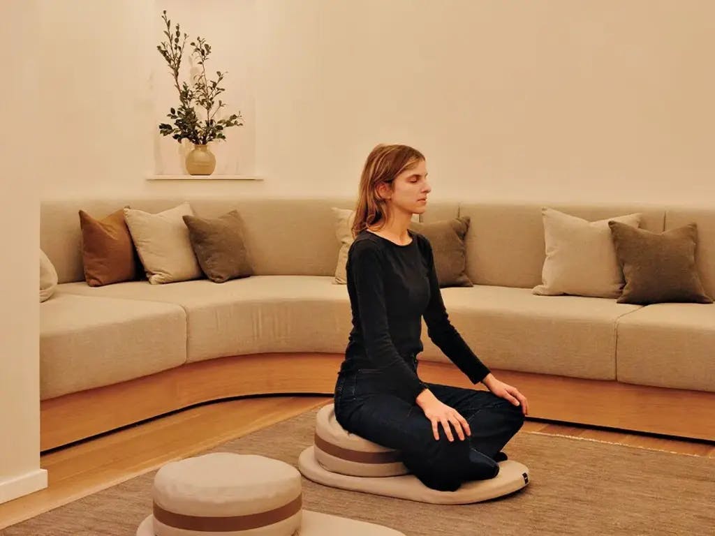 a women sitting on a cushion on the floor meditating
