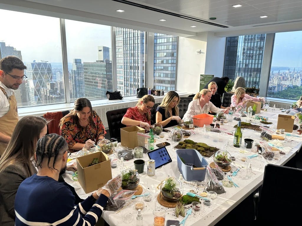 people sitting around a table making terrariums, with a skyline view in the background