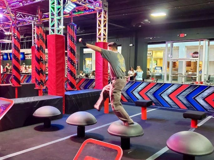 a man leaping between obsticles in a ninja warrior course