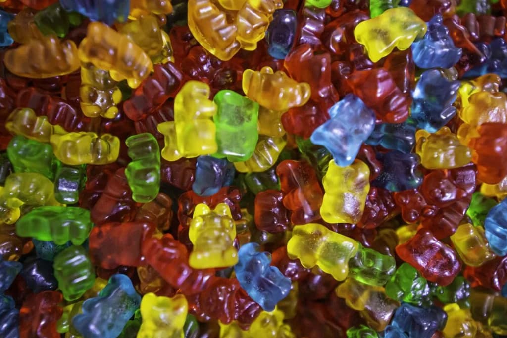 A pile of multicolored gummy bears, showcasing the vibrant reds, yellows, greens, and blues of the candies, scattered in a delightful, random pattern.