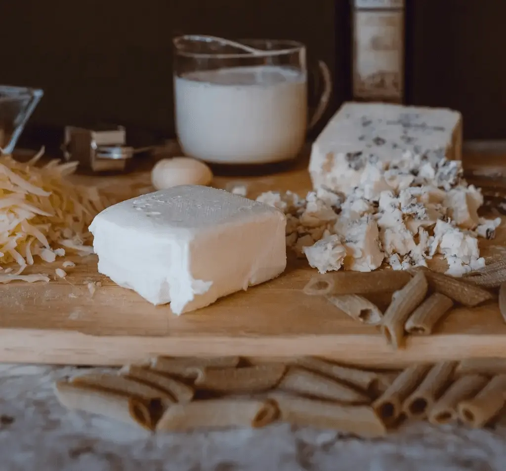 different cheeses and pasta on a cutting board