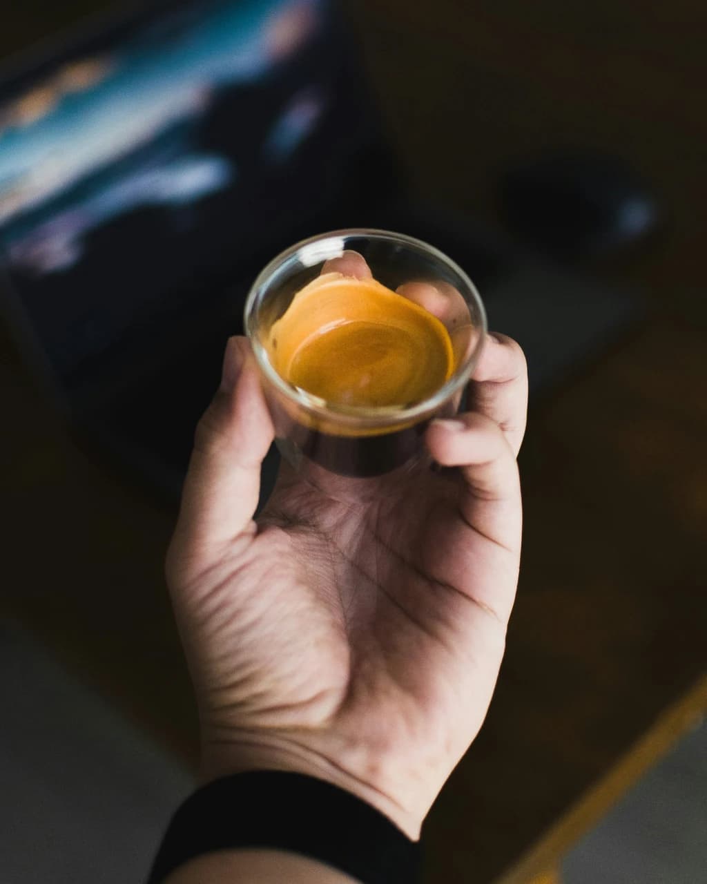 someone holding an expresso shot in thier hand