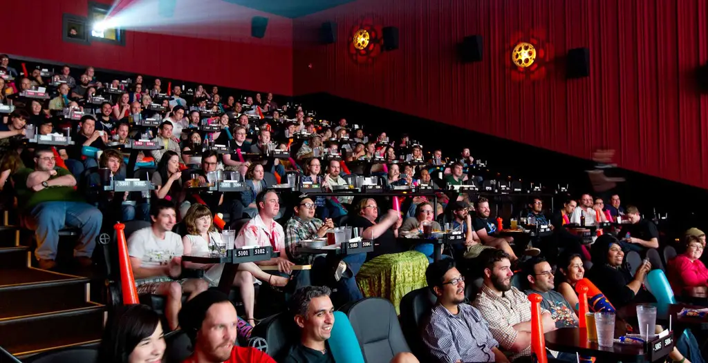 Another packed movie theater with attendees enjoying a film while dining in their seats.