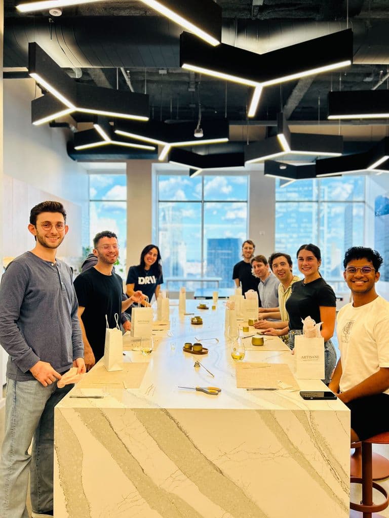 A group gathered around a modern marble table, smiling and ready for a hands-on workshop with gift bags and materials set up in front of them.