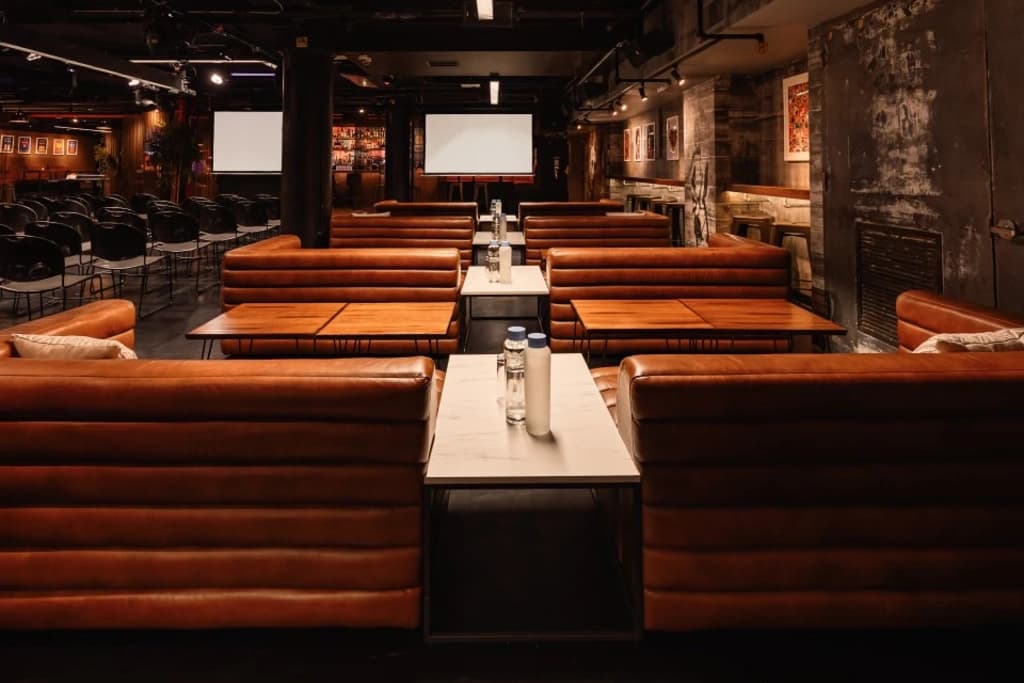 Cozy seating arrangement with leather couches and tables set up for a meeting or event in a stylish, dimly lit venue.